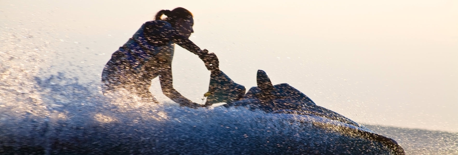 beautiful girl riding her jet skis in the sea at sunset